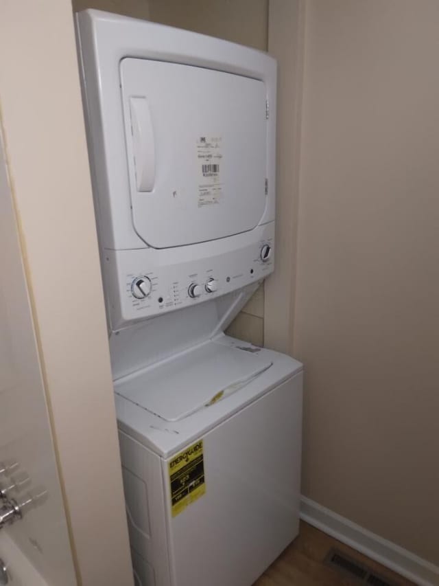 laundry area featuring dark hardwood / wood-style floors and stacked washer and clothes dryer