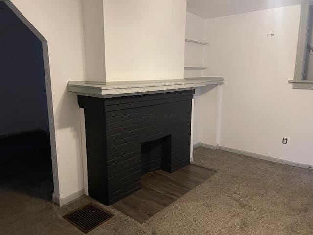 room details featuring carpet, a fireplace with flush hearth, visible vents, and baseboards