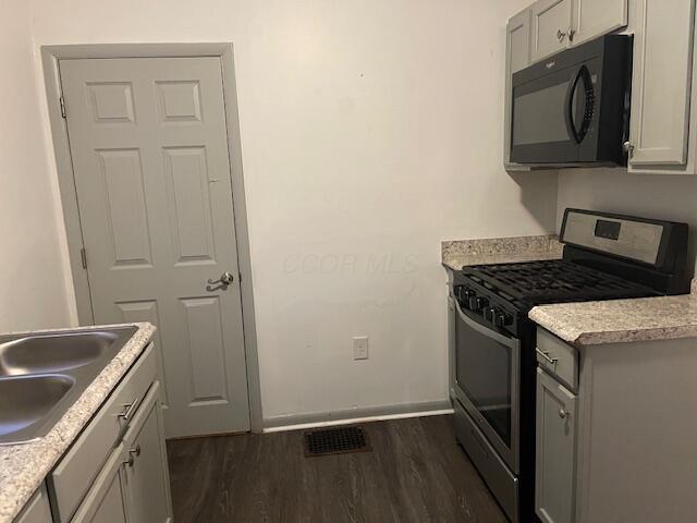 kitchen with gray cabinets, sink, dark wood-type flooring, and stainless steel stove