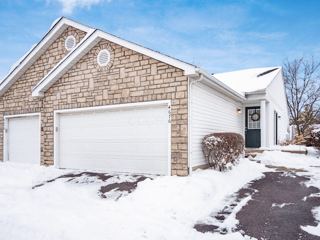 snow covered property with a garage