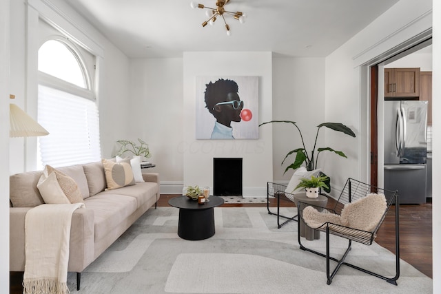 living room featuring plenty of natural light, light hardwood / wood-style floors, and a notable chandelier