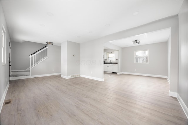 unfurnished living room featuring light hardwood / wood-style floors and sink