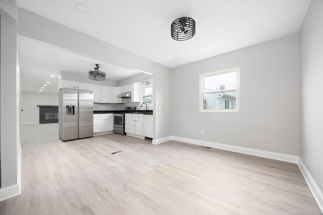 kitchen featuring light wood-type flooring, white cabinetry, backsplash, and appliances with stainless steel finishes