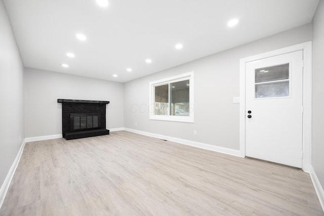 unfurnished living room with a fireplace and light wood-type flooring