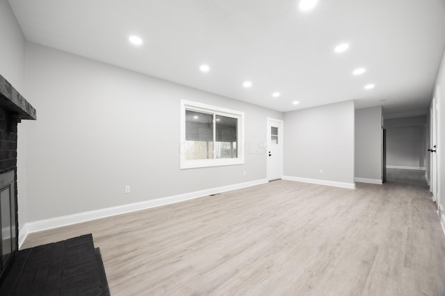 unfurnished living room with a fireplace and light hardwood / wood-style floors