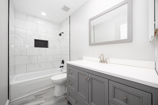 full bathroom featuring vanity, wood-type flooring, tiled shower / bath combo, and toilet