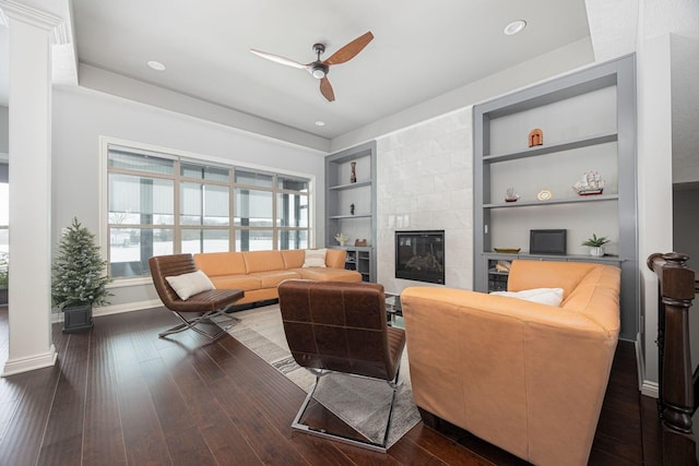 living room with ceiling fan, dark hardwood / wood-style floors, built in features, and a fireplace