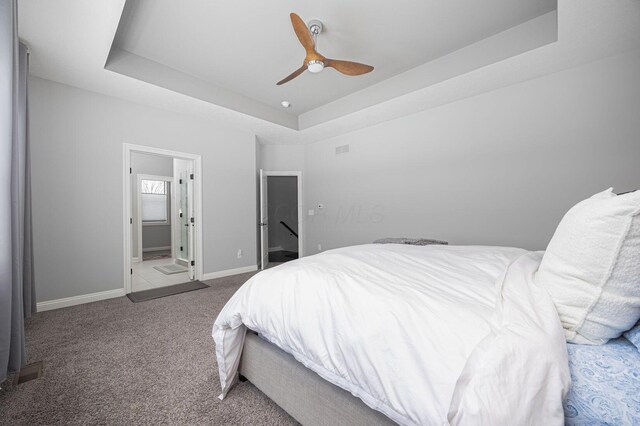 carpeted bedroom with a raised ceiling and ceiling fan