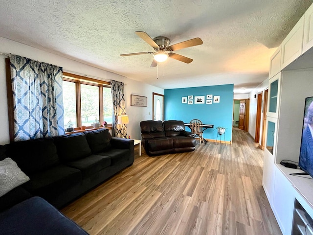 living room featuring a textured ceiling, light wood-type flooring, and ceiling fan