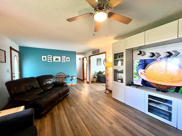 living room featuring a textured ceiling, hardwood / wood-style flooring, and ceiling fan