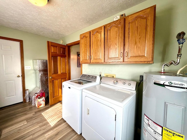 laundry room with cabinets, water heater, light hardwood / wood-style flooring, a textured ceiling, and washer and dryer