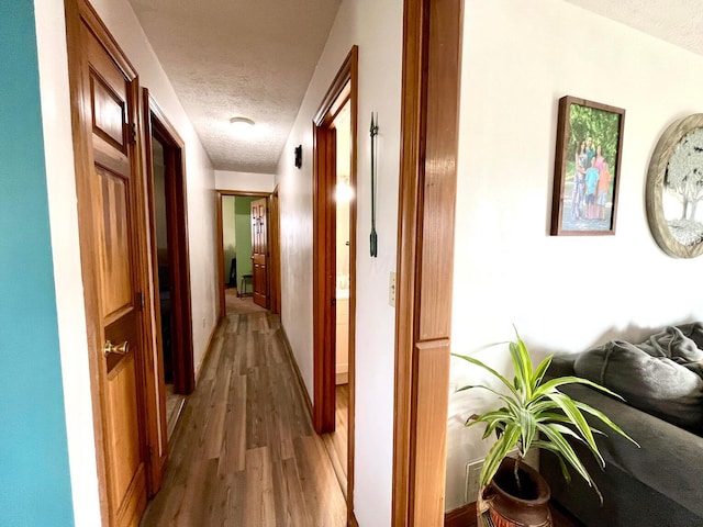 corridor featuring a textured ceiling and hardwood / wood-style flooring