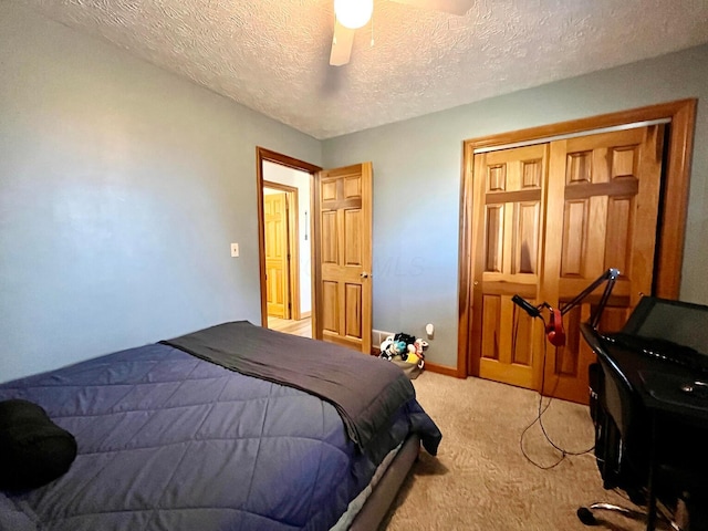 carpeted bedroom with ceiling fan, a closet, and a textured ceiling