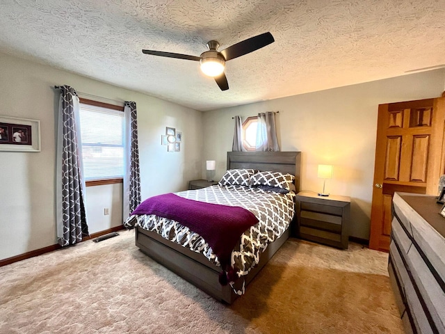 bedroom featuring ceiling fan, light colored carpet, a textured ceiling, and multiple windows