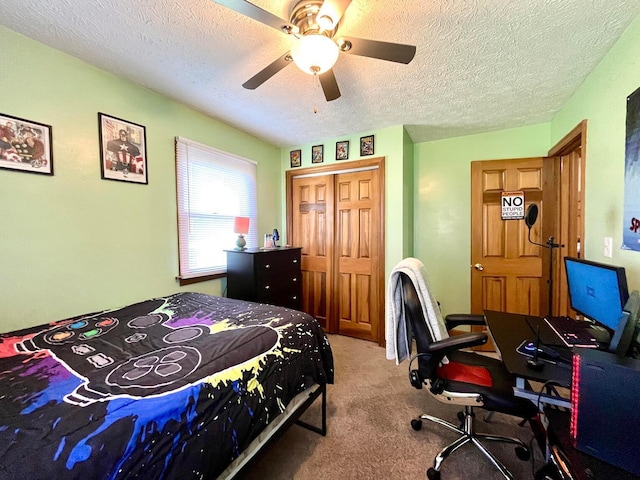 bedroom with a textured ceiling, light colored carpet, a closet, and ceiling fan