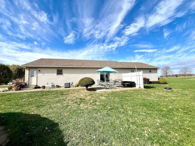 rear view of property with a lawn, central air condition unit, and a patio