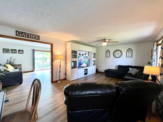 living room featuring ceiling fan, hardwood / wood-style floors, and a textured ceiling