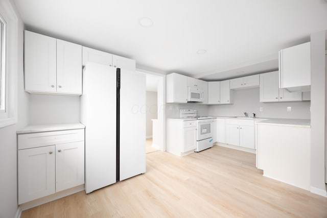 kitchen with white cabinets, white appliances, sink, and light hardwood / wood-style flooring