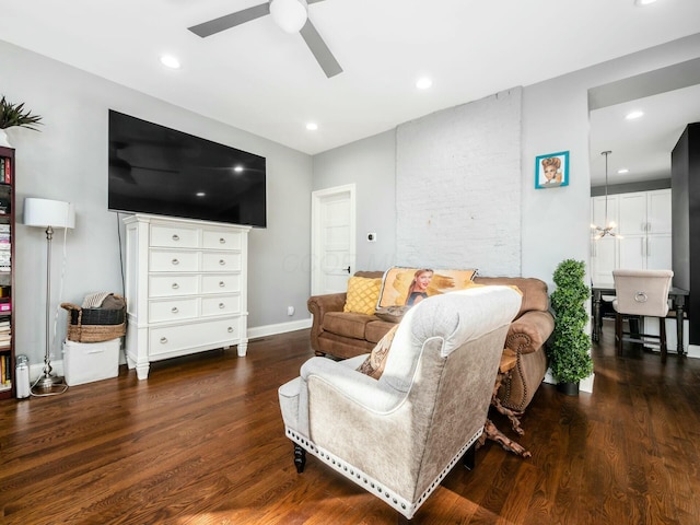 living room with ceiling fan with notable chandelier and dark hardwood / wood-style floors