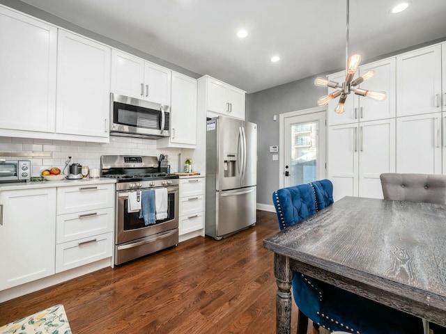 kitchen with white cabinets, stainless steel appliances, tasteful backsplash, hanging light fixtures, and dark hardwood / wood-style floors