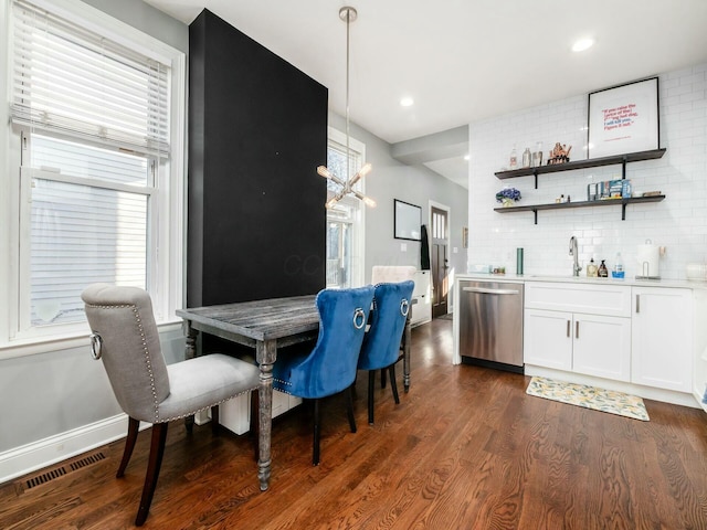 dining area featuring indoor wet bar, dark hardwood / wood-style floors, and an inviting chandelier