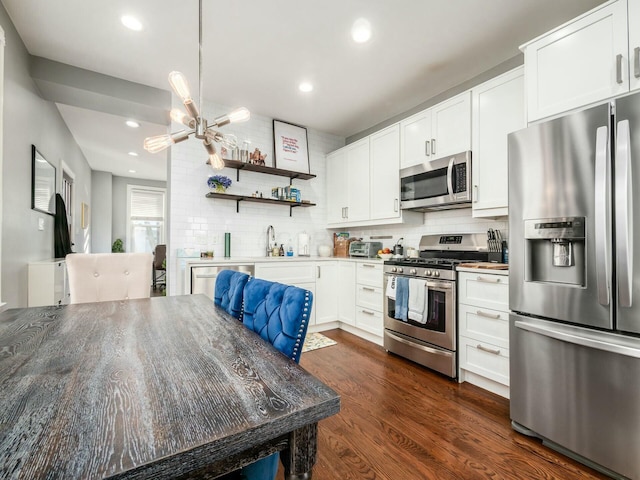 kitchen featuring dark hardwood / wood-style floors, appliances with stainless steel finishes, white cabinets, and tasteful backsplash