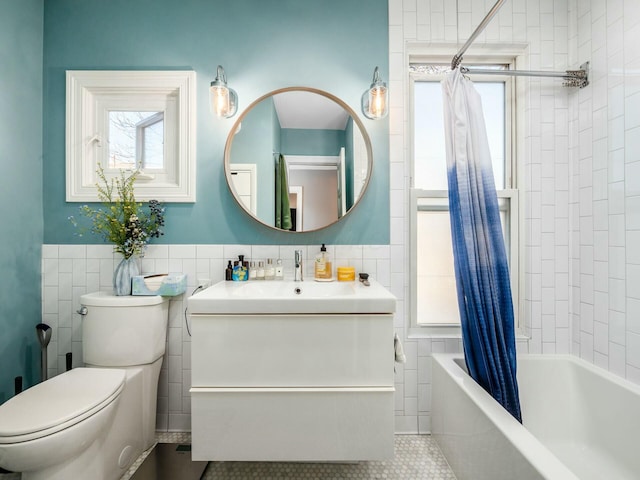 full bathroom with toilet, tile patterned flooring, shower / bath combination with curtain, tile walls, and vanity