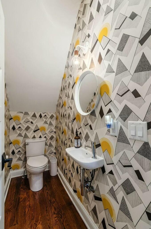 bathroom with toilet, vaulted ceiling, sink, and hardwood / wood-style flooring