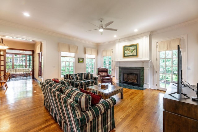 living room with light hardwood / wood-style flooring, a wealth of natural light, crown molding, and ceiling fan