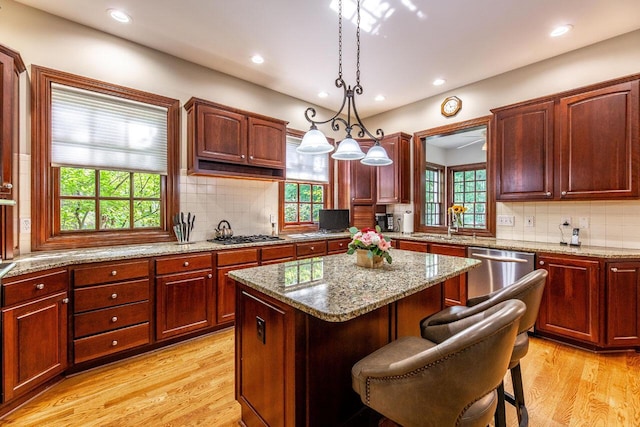 kitchen featuring pendant lighting, a breakfast bar, light wood-type flooring, appliances with stainless steel finishes, and a kitchen island