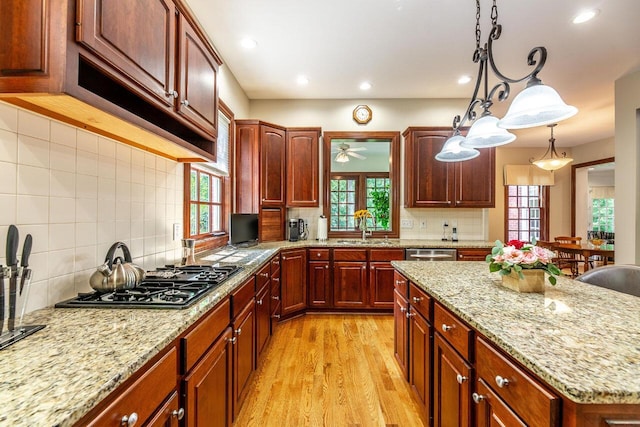 kitchen with backsplash, stainless steel appliances, ceiling fan, sink, and hanging light fixtures