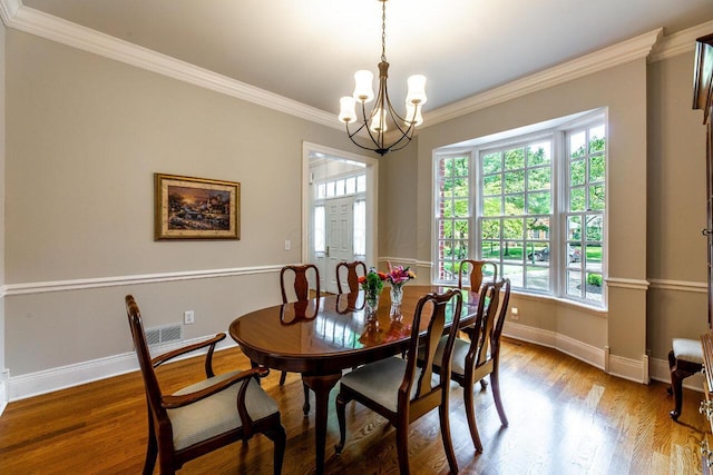 dining space featuring hardwood / wood-style flooring, a notable chandelier, and crown molding