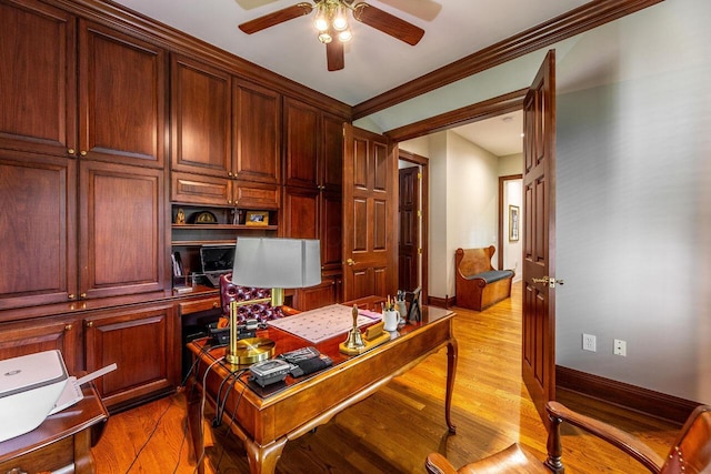 office space featuring built in desk, light hardwood / wood-style flooring, ceiling fan, and ornamental molding