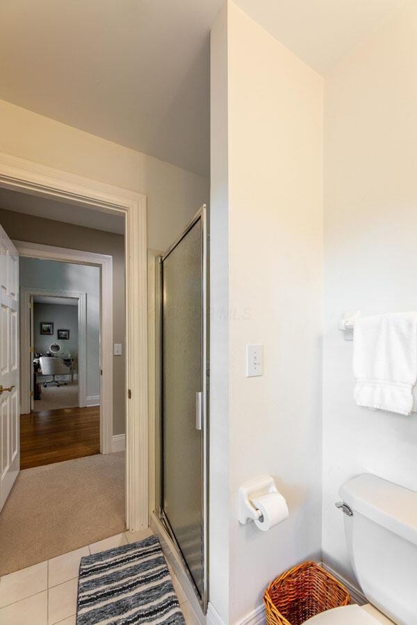 bathroom with tile patterned flooring, toilet, and walk in shower