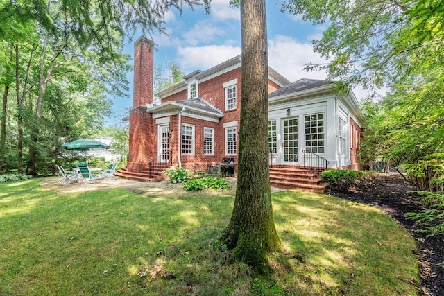 back of property featuring french doors, a patio area, and a lawn