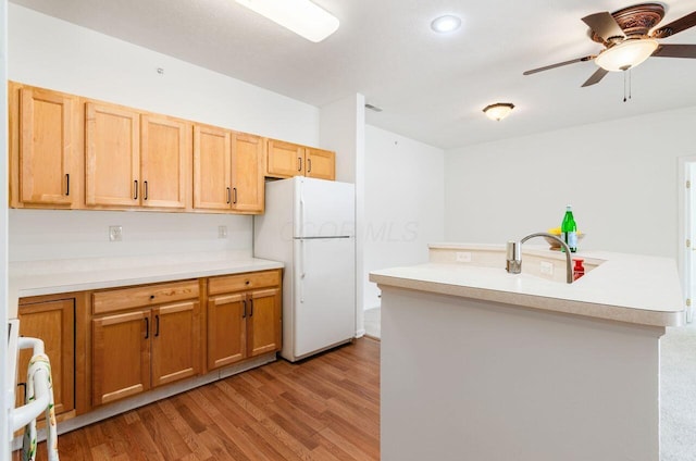 kitchen featuring kitchen peninsula, light wood-type flooring, ceiling fan, sink, and white fridge