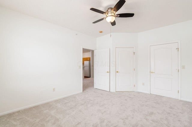 unfurnished bedroom with ceiling fan, light carpet, and white refrigerator