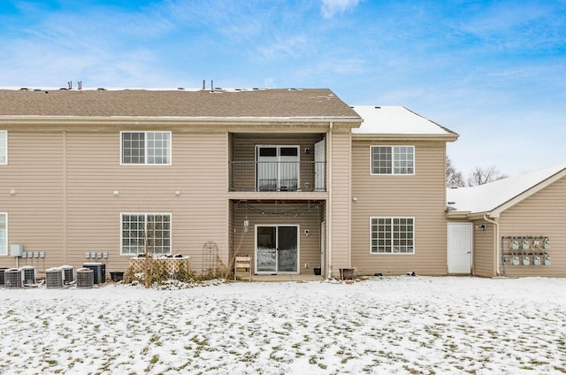 snow covered property with a balcony and central AC unit