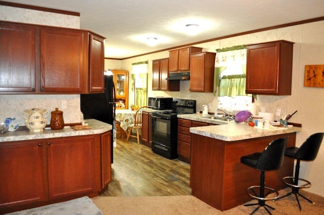 kitchen featuring black appliances, sink, ornamental molding, light hardwood / wood-style floors, and kitchen peninsula