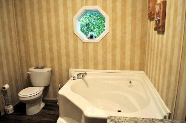 bathroom featuring a washtub, wood-type flooring, and toilet