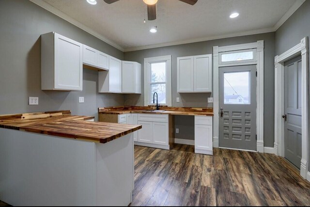 kitchen featuring white cabinetry, sink, wooden counters, dark hardwood / wood-style floors, and crown molding