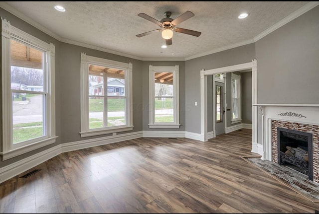 unfurnished living room featuring a fireplace, ceiling fan, a textured ceiling, and a wealth of natural light