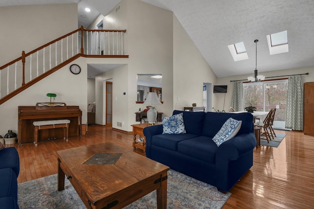 living room featuring wood-type flooring, a textured ceiling, high vaulted ceiling, and an inviting chandelier