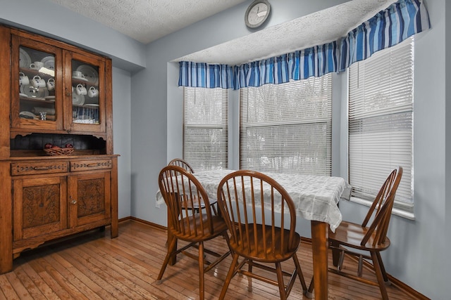 dining space with a textured ceiling and light hardwood / wood-style floors