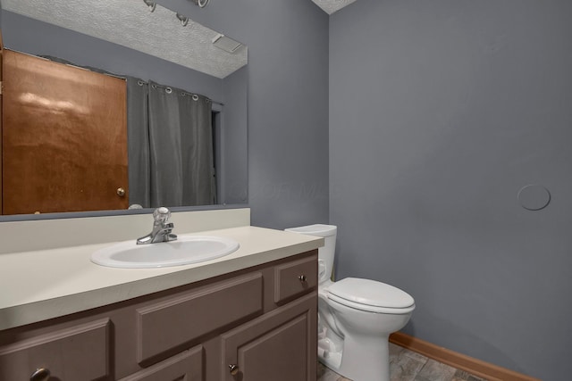 bathroom with a textured ceiling, vanity, and toilet