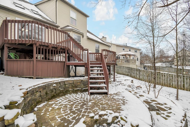 snow covered back of property featuring a deck