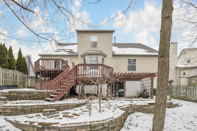 snow covered back of property featuring a pergola and a wooden deck