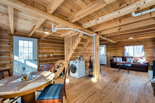 dining space featuring wooden walls, beam ceiling, wooden ceiling, washer / dryer, and light hardwood / wood-style floors