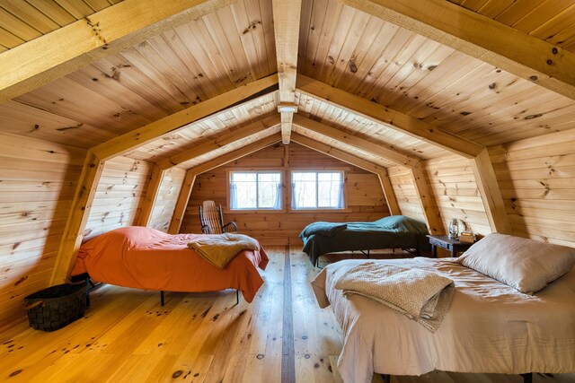 bedroom with vaulted ceiling with beams, wood walls, wood ceiling, and light wood-type flooring