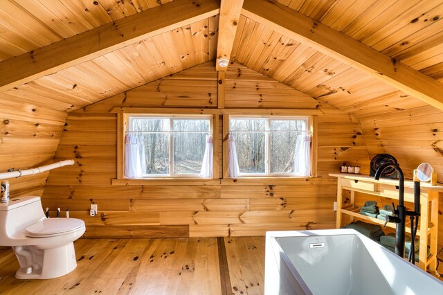 interior space with wooden ceiling, hardwood / wood-style flooring, vaulted ceiling with beams, a washtub, and toilet